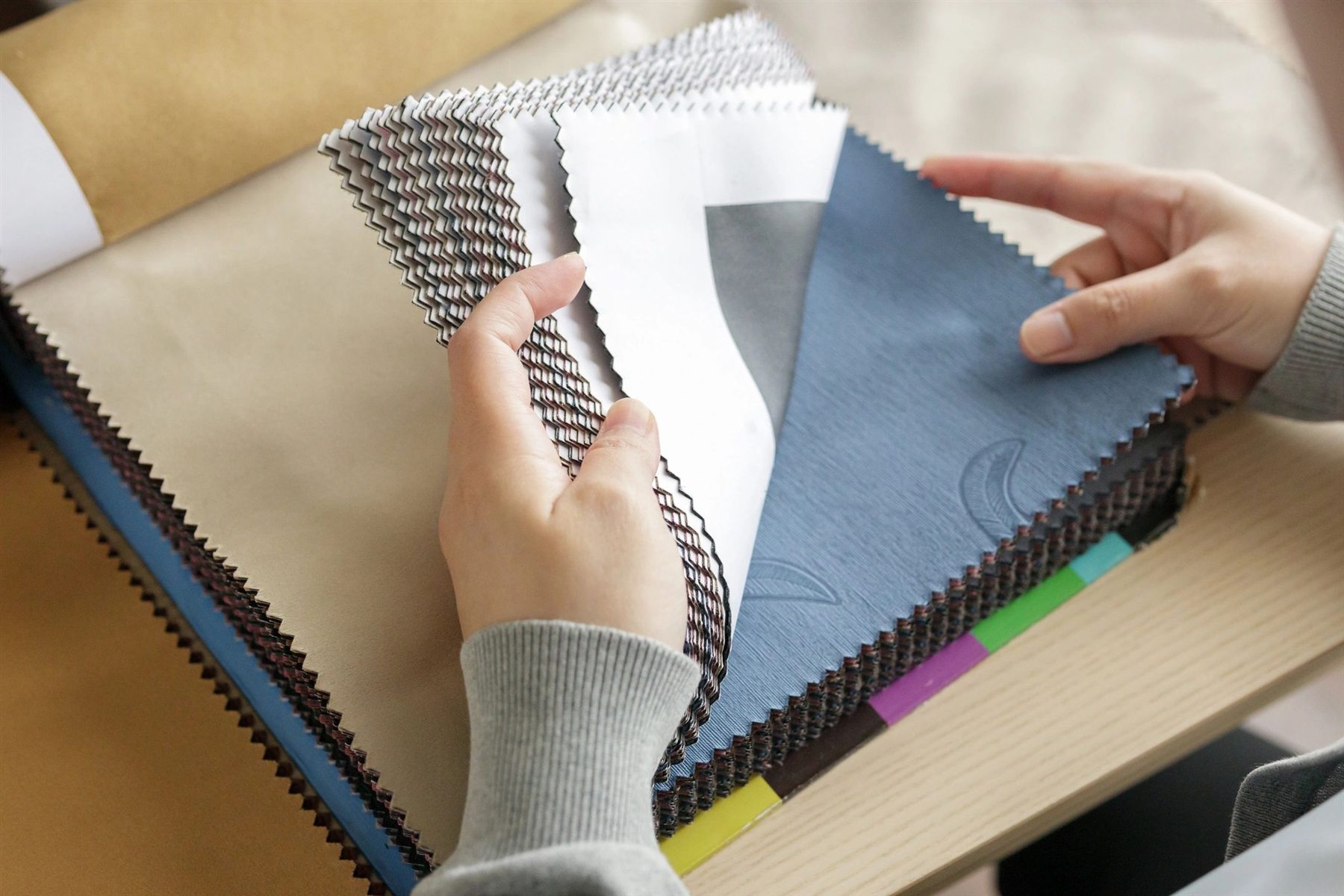 Designer reviewing physical fabric colour samples against a digital reference